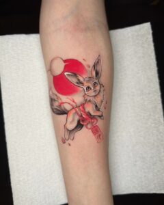Anime-style tattoo of Eevee with red sun and Japanese details by Tizio Art