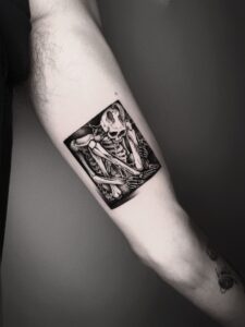 Blackwork tattoo of a detailed skeleton composition on the inner arm