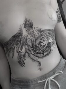 Large black tattoo of a phoenix rising across the torso – Tizio Art