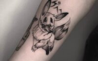Blackwork tattoo of a dark Eevee with Japanese lettering on forearm