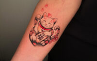 Maneki Neko Japanese tattoo in Antwerp with cherry blossoms, symbolizing luck.